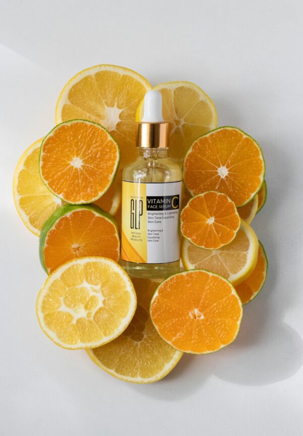 Vitamin C serum bottle surrounded by fresh orange and lemon slices.
